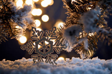 在雪地里，用云杉枝條和模糊的圣誕彩燈把裝飾過的雪花包在一起 