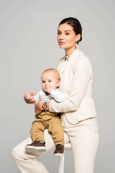 漂亮的女商人，穿著西服，坐在凳子上抱著孩子，與灰色隔絕