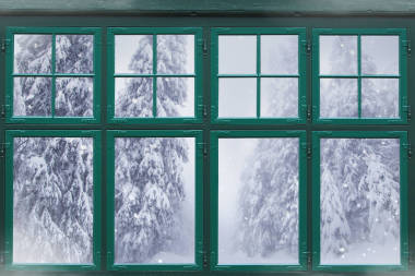 窗外的窗框，外面有白雪覆蓋的冷杉樹 