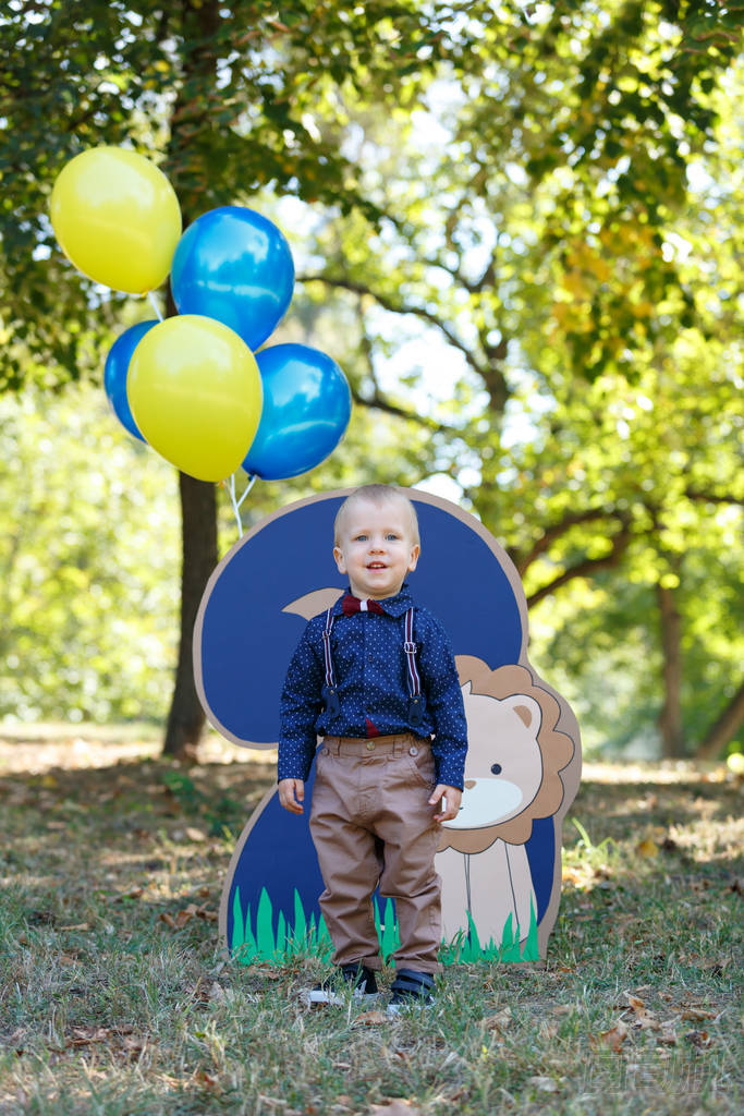 一個(gè)以自然為背景的可愛小男孩的畫像。 兩歲男孩的生日。 用獅子和氣球裝飾二號(hào)