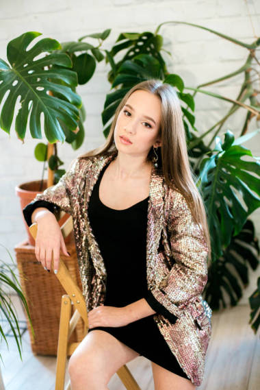 少女，長發(fā)，身穿黑色連衣裙，穿著閃閃發(fā)光的夾克，在熱帶植物中的圖迪亞。 晚禮服