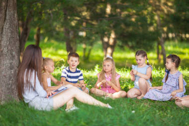 孩子們在公園里和老師一起在一個綠色的l上上課