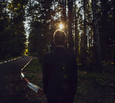 穿着黑色西装的男人构成后面，看着快要升起的太阳在公园
