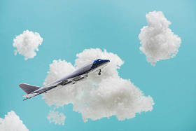 玩具飞机在白色蓬松的云彩中飞行，这些云彩是用蓝色孤立的棉毛制成的