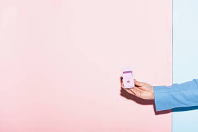 男子手持盒子的裁剪视图订婚戒指在蓝色和粉红色的背景上