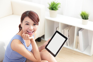 快樂的女人在沙發(fā)上使用 tablet pc