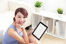 快乐的女人在沙发上使用 tablet pc