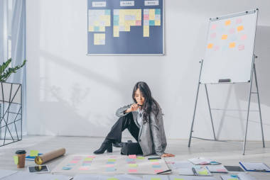 漂亮的亞洲scrum大師坐在地板上旁邊是小玩意和便利貼