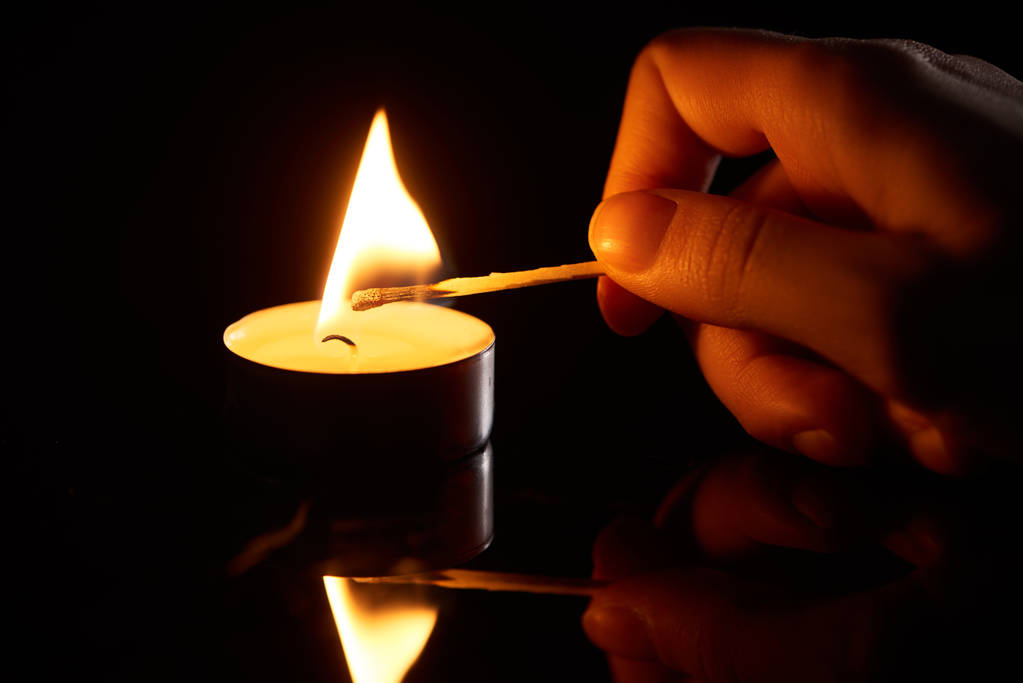 选择重点的女人点燃蜡烛，火柴用黑色隔