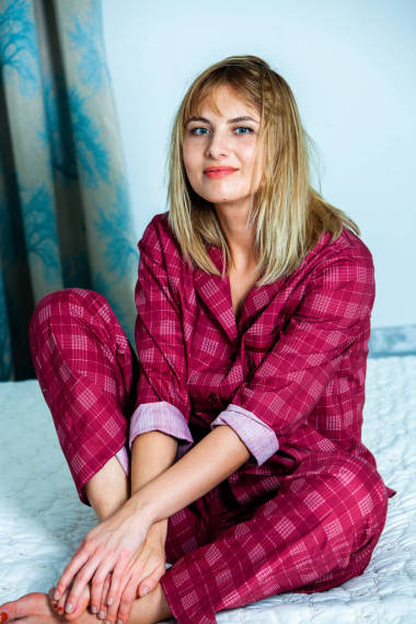 年輕漂亮的女人在燈光室醒來。躺在睡衣床上的放松的女人。早上好概念-年輕的女人醒來, 在她的臉上快樂的笑容