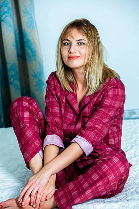 年轻漂亮的女人在灯光室醒来。躺在睡衣床上的放松的女人。早上好概念-年轻的女人醒来, 在她的脸上快乐的笑容