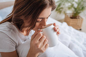 迷人的年轻女子在卧室喝茶 图片