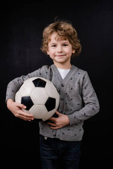 4.快樂的小男孩，穿著便衣，一個接一個地拿著足球站在鏡頭前