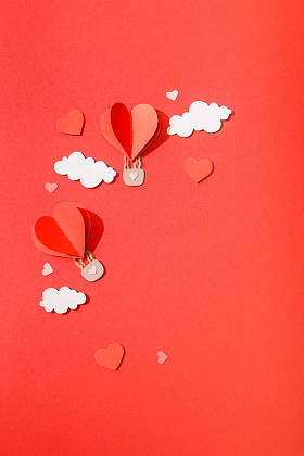 红色背景云彩中纸心形气球的顶部视图