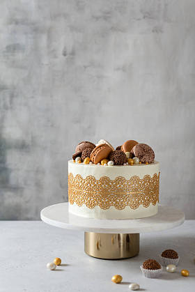 漂亮的结婚蛋糕,装饰着金黄色的花边,巧克力糖果和金银花. 糕点，糖果，生日卡片的概念。 复制空间