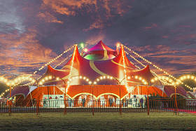 在警告的日落和混乱的天空下马戏团帐篷的夜景