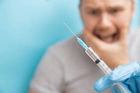男子是恐惧和哭泣从注射器与疫苗医生预约。 恐惧症的概念