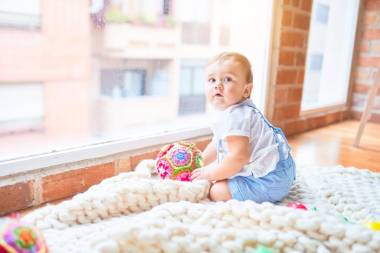 幼稚園時，漂亮的幼兒坐在毛毯上透過窗戶眺望