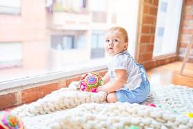 幼稚园时，漂亮的幼儿坐在毛毯上透过窗户眺望