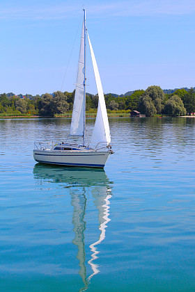 在清晨在山上的湖上扬帆的船