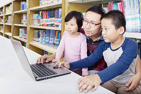 父亲用笔记本电脑帮助孩子们学习