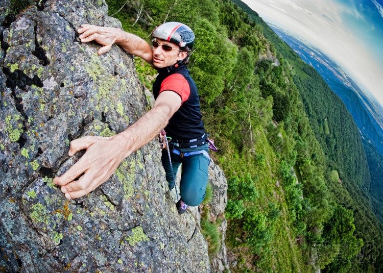年輕的白人男子攀爬陡峭壁圖片