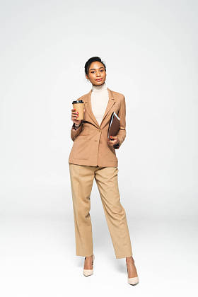 漂亮的非洲裔美国女商人拿着白色的文件夹和纸杯 