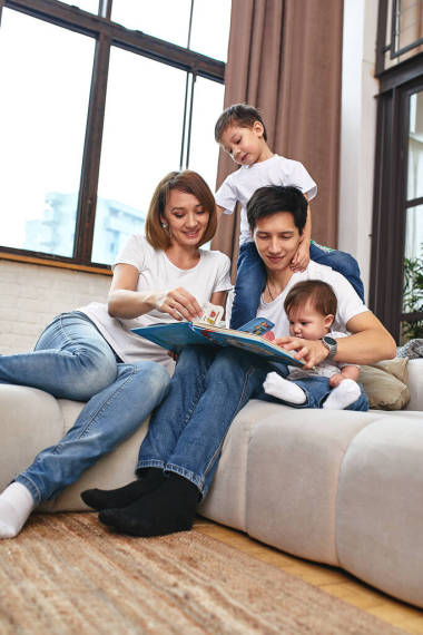 快乐的国际家庭概念。爸爸、妈妈、儿子和小女儿在家里摆着相机，正在为人父母。家庭假日、养育子女、概念儿童和父母