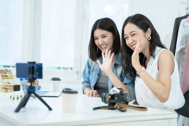 在社交媒體上，有魅力的亞洲女人通過智能手機在線銷售產(chǎn)品。年輕的女性時尚博客在網(wǎng)上直播服裝