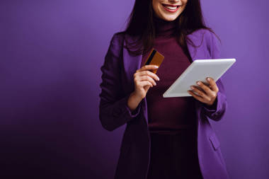 帶著紫色背景的數(shù)碼平板電腦和信用卡微笑的女人的剪影