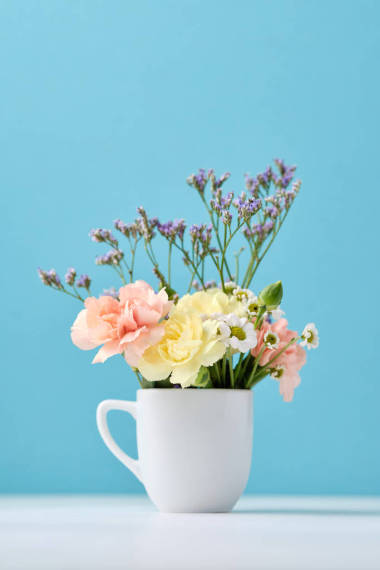 藍(lán)色背景的白色杯子中的美麗的小花