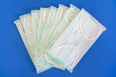 藍(lán)色表面上有簡(jiǎn)單的白色防風(fēng)面具.白色背景的醫(yī)用防護(hù)面罩。醫(yī)用外科流感防護(hù)面罩紡織品濾清器的封堵