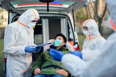 穿着防护服的人在户外帮助男人