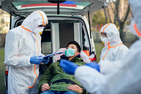 穿着防护服的人在户外帮助男人