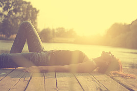 放松年轻的女子，在木码头在湖在日落的旧照片