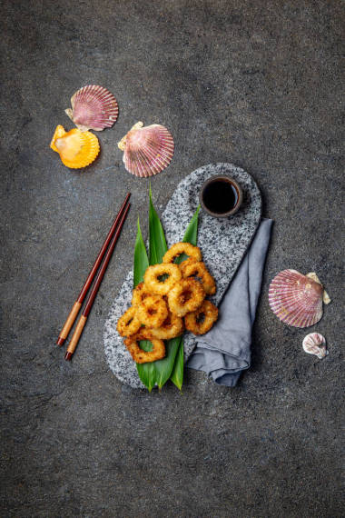 用热带叶子装饰的石板上的炸鱿鱼戒指。亚洲食品概念。顶视图
