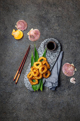 用热带叶子装饰的石板上的炸鱿鱼戒指。亚洲食品概念。顶视图