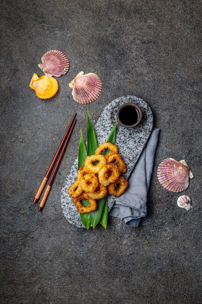 用热带叶子装饰的石板上的炸鱿鱼戒指。亚洲食品概念。顶视图