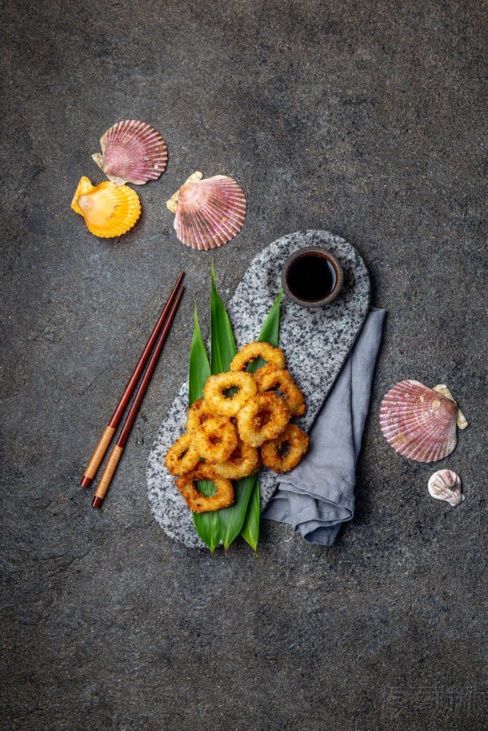 用熱帶葉子裝飾的石板上的炸魷魚戒指。亞洲食品概念。頂視圖