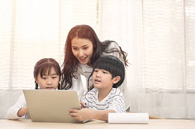 有孩子的快乐的亚洲家庭和他们的妈妈用电脑在家里做作