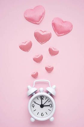 创意概念假日情人节爱的照片与时间时钟手表在粉红色的背景