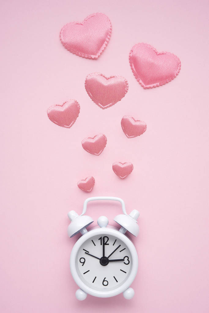 创意概念假日情人节爱的照片与时间时钟手表在粉红色的背景 创意概念假日情人节爱的照片与时间时钟手表在粉红色的背景