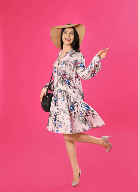 穿着粉色背景花纹连衣裙和草帽的年轻女子