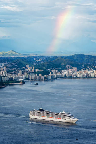 一艘背景为彩虹的在里约热内卢航行的游船，巴西