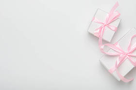 白色背景上有粉色带子的礼品盒。概念节日礼物，恭喜你。顶视图、复制空间、平面布