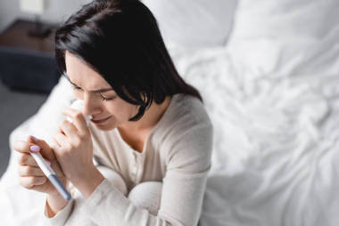 心煩意亂婦女哭泣和進行妊娠測試的俯視圖 