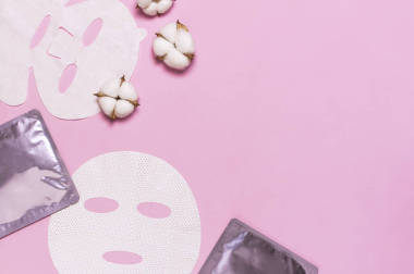 面料面膜,棉花粉紅底色.采購(gòu)產(chǎn)品天然化妝品的概念，面部護(hù)理，溫泉，面霜，女人的美容配件。平面放置頂部視圖復(fù)制空間?；瘖y品模特兒