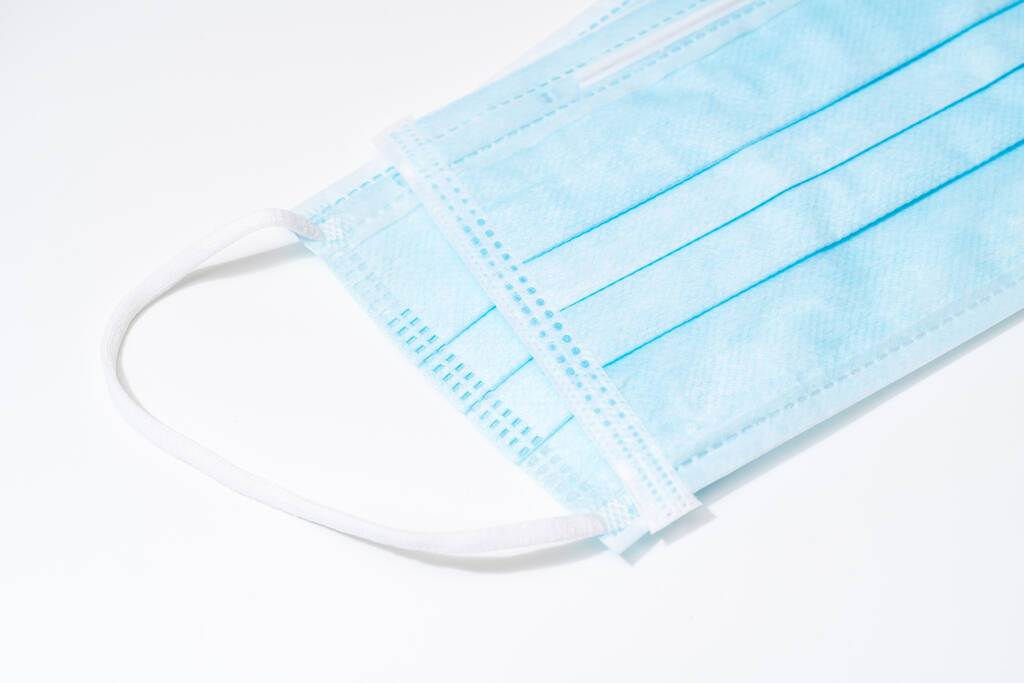 带橡胶耳带的外科口罩。典型的3层外科口罩盖住口鼻。程序面罩从细菌。保护概念 带橡胶耳带的外科口罩。典型的3层外科口罩盖住口鼻。程序面罩从细菌。保护概念