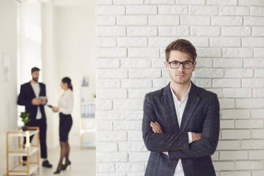 嚴(yán)肅的商人穿著休閑裝站在白墻上的一間白色辦公室