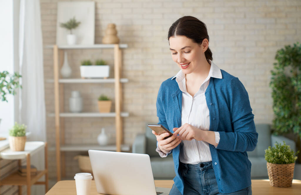 在家里的笔记本电脑上工作的快乐而随意的漂亮女人 在家里的笔记本电脑上工作的快乐而随意的漂亮女人